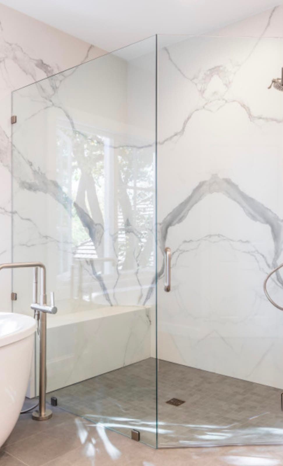 Luxury shower with marble slab walls, frameless glass panel, and freestanding tub installed by Costa Bathroom Remodel in Parrish, Florida